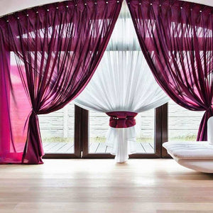 Moderne leefruimte met grote glazen schuifdeur, magenta gordijnen, witte L-bank en zwarte eettafel. Eigentijdse inrichting, ideaal voor kunstwerken van degrootmeesters.com.