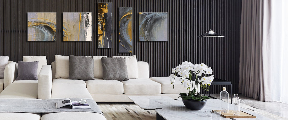 Een moderne woonkamer met een beige hoekbank, abstracte kunstwerken boven de bank, marmeren salontafel met orchideeën en glazen set, en een strakke hanglamp.