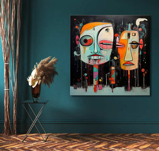 Abstract painting titled Corneille signature - Habitants du Dessert with colorful faces, hung on a teal wall, next to a black metal table and pampas grass.