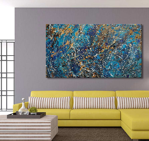 Jackson Pollock signature – Living Daylights schilderij: abstract kunstwerk met blauwe, witte, gouden en zwarte tinten, opgehangen boven een gele bank in een moderne woonkamer.