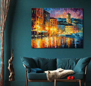 Handgeschilderd olieverfschilderij Cannes in de stijl van Leonid Afremov, toont een sfeervol impressionistisch tafereel van een stad bij schemering, opgehangen boven een teal loveseat.