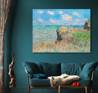 Claude Monet's Cliff Walk at Pourville oil painting, Impressionist seascape, hangs above a teal sofa in a cozy living area.