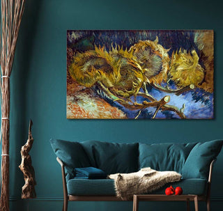 Framed Vincent van Gogh painting Vier Uitgebloeide Zonnebloemen in impasto style above a teal sofa with a grey throw and blue cushion, enhancing a cozy living space.