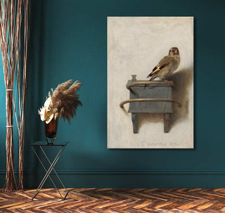 Carel Fabritius's The Goldfinch reproduction, hand-painted oil on canvas, displayed on a deep teal wall, beside a black side table with dried grasses.