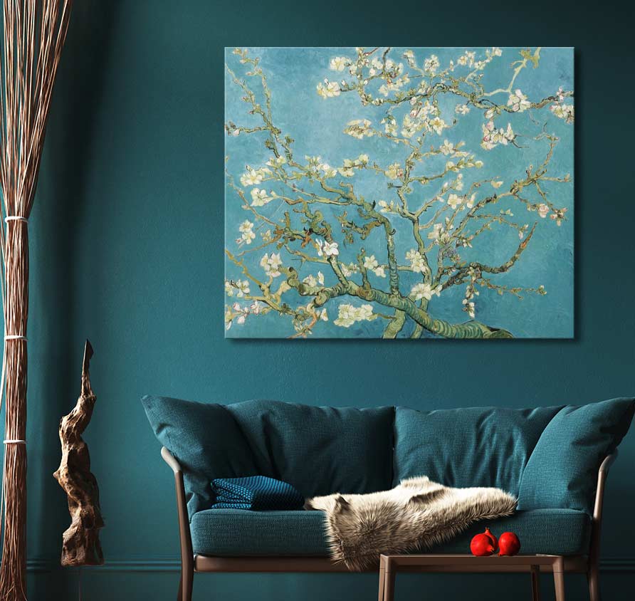 Vincent van Gogh - Amandelbloesem canvas met impressionistische bloemen tegen blauwe achtergrond, opgehangen boven een blauwgroene loveseat met bijpassende kussens in sfeervolle ruimte.