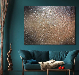Goudbladeren - Olieverf op canvas: Abstract schilderij met metalen bladtextuur in brons en zilver, boven een teal tweezitsbank in een moderne, natuurlijke woonkamer.