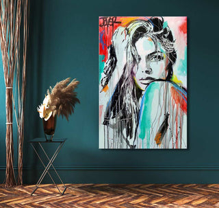 Hand-painted Pop Art portrait In Spirit by Loui Jover, depicting a woman's face with expressive drip technique. Displayed against a teal wall with minimal decor.