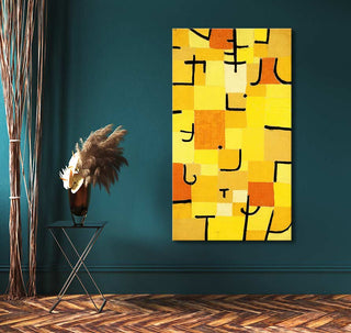 Paul Klee's Beelden in Geel abstract painting with yellow, orange, and black forms, displayed in a modern setting with a side table and pampas grass.