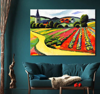 August Macke’s vibrant expressionist painting, Landschap met Kerk en Weg, displayed above a teal sofa in a modern living room, enhances decor with bold countryside imagery.