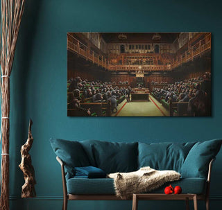 Banksy - Devolved Parliament oil painting depicting apes in a parliamentary setting, framed above a sofa with a cozy throw and apples on a coffee table.