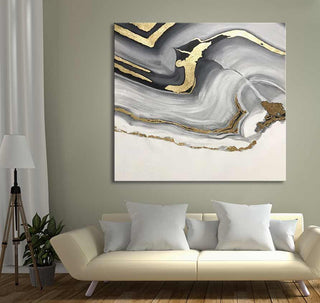 Gelaagd Goud 2 - Acrylverf op canvas: abstract schilderij met gouden accenten op grijs en wit, boven een crèmekleurige bank. Perfect voor modern interieurdesign.