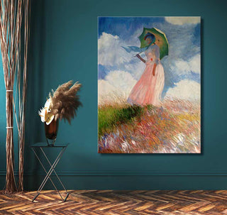 Handgeschilderd olieverfschilderij Dame met Parasol van Claude Monet, opgehangen tegen een teal-groene muur naast een zwart metalen bijzettafeltje met pampasgras.